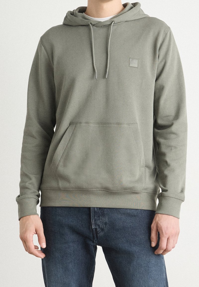 Sudadera con capucha de color verde oliva hecha de tela suave, con bolsillo frontal, capucha ajustable con cordón y puños y dobladillo acanalados.