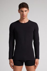 Czarna longsleeve koszula z miękkiego materiału, z okrągłym dekoltem i dopasowanym krojem. Noszona z czarnymi szortami, minimalne detale przeszycia.