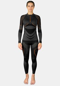 Black thermal suit with long sleeves and pants, featuring orange accents and textured sections. Zipper at neck for easy wear.