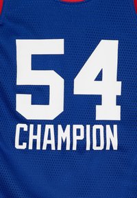 Camiseta de malla azul con el número blanco "54" y la palabra "CAMPEÓN" en letras grandes, con acentos rojos en el escote.