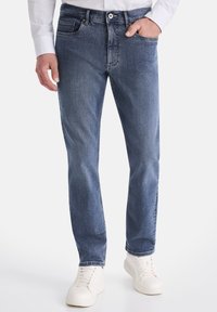 Hellblaue Jeans aus Denim mit geradem Schnitt, fünf Taschen und subtilen Ausbleichungen. Kombiniert mit weißen Sneakers, die einen lässigen Look zeigen.