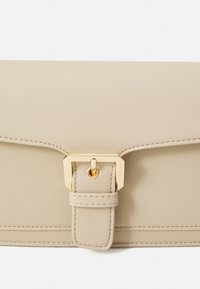 Pochette en cuir beige avec coutures détaillées et une boucle rectangulaire dorée centrée sur le rabat avant.