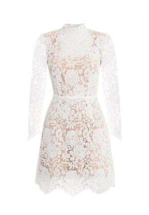 Biała koronkowa sukienka z wysokim kołnierzem i długimi rękawami, zdobiona kwiatowymi wzorami i falowanym brzegiem. Wąski pasek podkreśla talię.