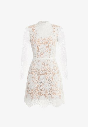Biała koronkowa sukienka z wysokim kołnierzem i długimi rękawami, zdobiona kwiatowymi wzorami i falowanym brzegiem. Wąski pasek podkreśla talię.