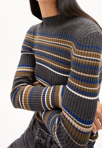 Pull à col montant côtelé en gris foncé avec des rayures horizontales marron, bleu et blanc. Manches près du corps et tissu texturé.