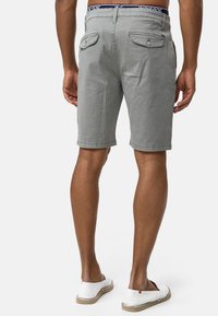 Szare bawełniane szorty o fakturowanym wzorze, z dwoma tylnymi kieszeniami, podwiniętym dołem i kontrastującą talią. Nosi się je z białymi butami wsuwanymi.