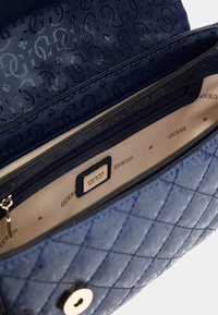 Sac à main matelassé navy avec logos en relief, fermeture à snap en métal doré et intérieur beige avec un compartiment zippé.
