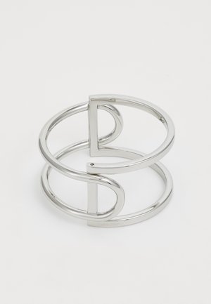 Silberner Metallarmreif mit einem Doppel-Schleifen-Design, glatter, glänzender Oberfläche und einem minimalistischen geometrischen Akzent.