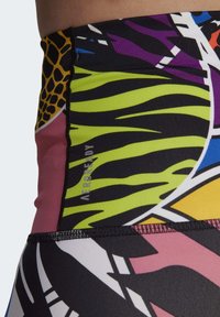 Leggings taille haute avec un motif animalier vibrant en vert, rose, violet et jaune, fabriquées à partir d'un tissu extensible et évacuant l'humidité.