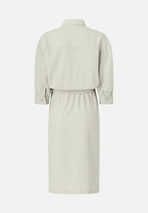 Vestito camicia beige chiaro a maniche lunghe con polsini abbottonati, colletto e vita aderente visto da dietro su uno sfondo semplice.