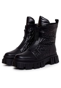 Botines negros hasta el tobillo hechos de material sintético acolchado con suela gruesa, con cremallera lateral y tacón pronunciado.