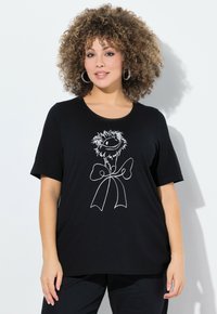 Camiseta negra de algodón, con un gráfico floral blanco y diseño de cinta. Mangas cortas, cuello redondo, ajuste relajado.