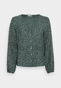 Blouse verte boutonnée avec un motif de feuilles sur un fond noir, manches longues et col en V. Fabriquée en tissu léger.