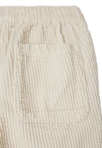 Pantalon en velours côtelé crème, présentant un motif côtelé texturé, une taille élastique et une unique poche arrière. Tissu doux avec une finition lisse.