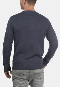 Maglione lavorato a maglia blu Navy con colletto rotondo, maniche lunghe e orlo a coste. Il tessuto appare liscio con una sottile texture.