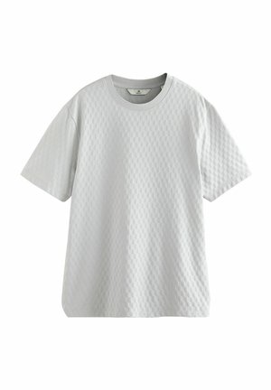 T-shirt gris clair à manches courtes en tissu texturé avec un motif à carreaux, présentant un col rond et une coupe décontractée.