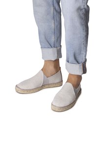 Světlé šedé plátěné espadrilky mají elastickou boční část a jutu na podrážce. Jsou nošeny s mírně ohrnutými světle modrými džíny.
