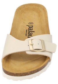 Gräddfärgad sandal med en lätt, texturerad innersula. Har ett brett rem med en guldfärgad metalspänne och en korkbas för komfort.