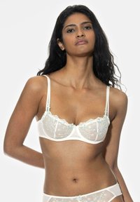 Biały koronkowy stanik z kwiatowym haftem w odcieniach niebieskiego i zielonego, cienkimi ramiączkami oraz falbaniastymi brzegami, prezentujący półprzejrzysty design.