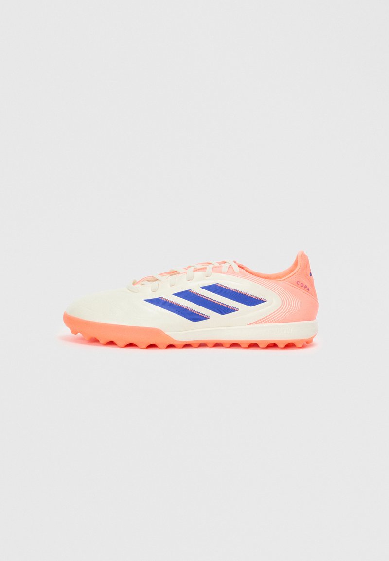 Botas de fútbol blancas con suela y acentos en coral brillante, que presentan tres franjas azules, sistema de cordones y un diseño superior texturizado para tracción.