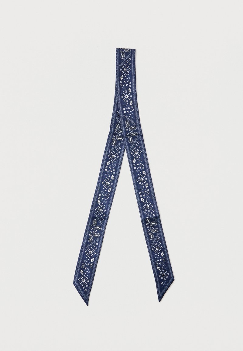 Écharpe étroite bleu marine avec motifs cachemire blancs et motifs géométriques, portée en boucle pliée sur fond blanc.