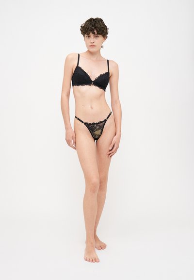 Black lace bra and thong set featuring a floral pattern, adjustable straps, and scalloped edges. Soft texture with a sheer finish.