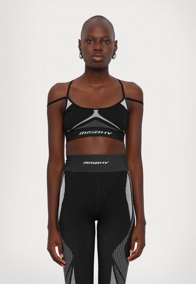 Soutien-gorge de sport noir avec des bretelles ajustables et des inserts en maille, associé à des leggings noirs taille haute ornés d'accents gris et d'un motif.