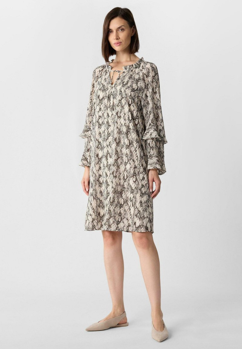 Sukienka z długim rękawem w wężowy wzór, z falbankami przy dekolcie i rękawach, luźnym krojem i fasonem w kształcie litery A w tonacjach beżu i czerni.