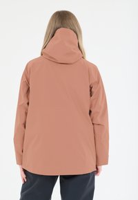 Vedeněodolná bunda v tlumeně korálové barvě, s utaženou kapucí, dlouhými rukávy a rovnými lemy. Hladká textura s utěsněnými švy.