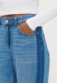 Τζιν παντελόνια σε διάφορες αποχρώσεις του μπλε με ίσια γραμμή. Διαθέτουν μπροστινές τσέπες, ραφές με χάλκινο νήμα και μοντέρνα ψηλή μέση.