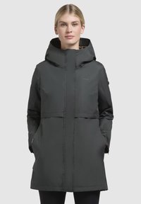 Zwarte caputch jacket met een ritssluiting, voorzien van twee zijzakken, een middellange snit en een subtiele logo op de borst. Textuur voering zichtbaar in de capuchon.