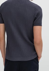 Navy short-sleeve knitted sweater with a textured ribbed pattern, featuring a fitted silhouette and a rounded neckline.