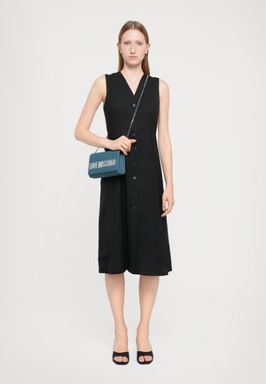 Black A-line dress with a v-neck, button-down front, and side pockets; paired with a teal handbag featuring "LOVE MOSCHINO" in silver.