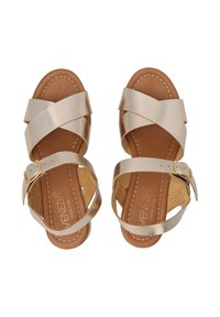 Gouden metallic sandalen met kruislings straps, bruine leren binnenzool en een zijgesp. Gevestigde details langs de zool.