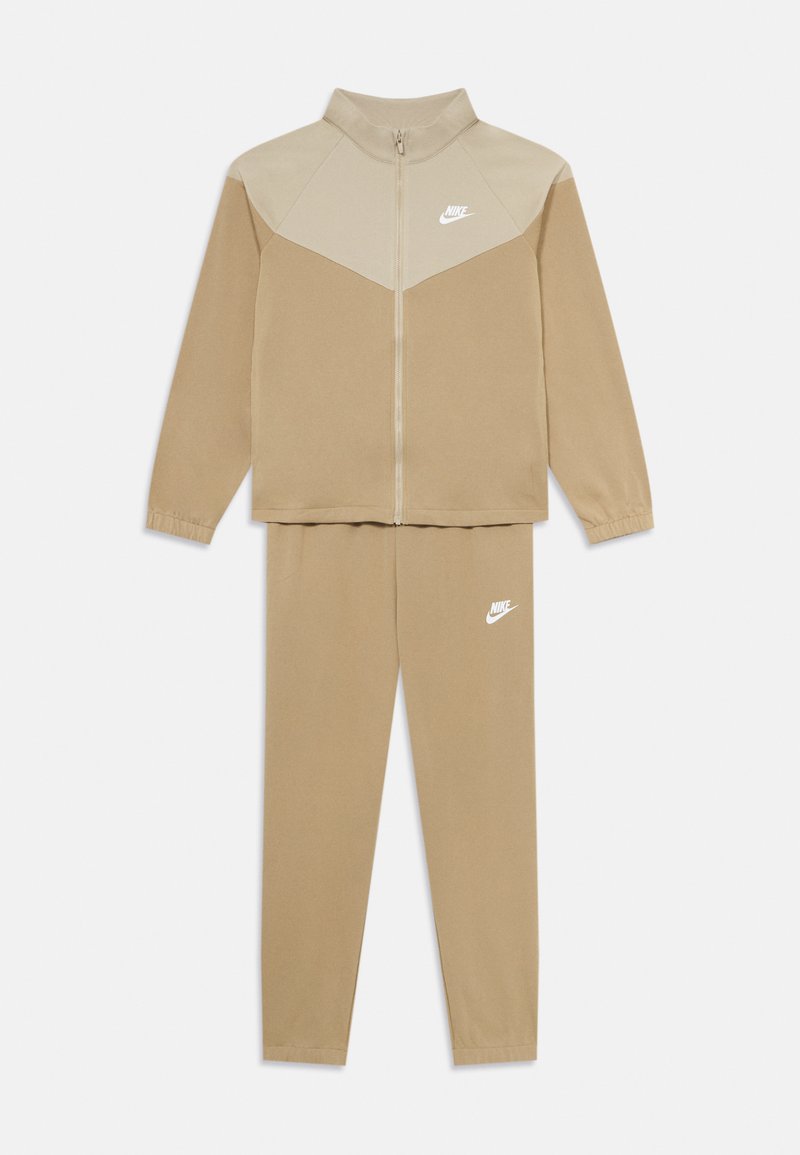 Fato de treino Nike de duas peças em bege, com casaco com fecho éclair e yoke mais claro, e calças combinando, ambos com logos da Nike em branco.