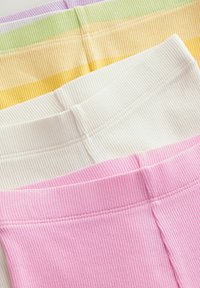 Geribbelde leggings in vier kleuren: roze, wit, geel en groen. Elk heeft een rekbare tailleband en is keurig gevouwen.