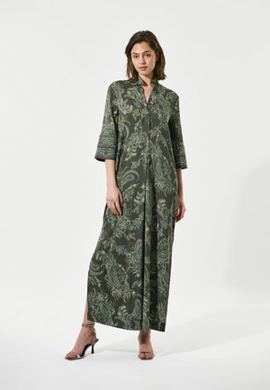 Robe longue verte à motif paisley avec un col et des manches trois-quarts, dotée d'une fermeture à boutons sur le devant et d fentes latérales. Texture de tissu douce.
