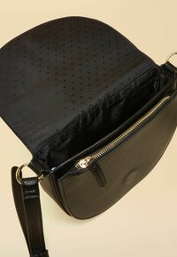 Čierna kabelka cez rameno vyrobená z textúrovaného materiálu, vybavená vreckom so zipsom, hladkou podšívkou a kovovými ozdobami. Dizajn s otvorenou klopou.