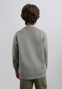 Lichtgroene sweatshirt met een gestructureerde stof, raglanmouwen en geribbelde manchetten. De achterkant heeft een glad en eenvoudig ontwerp.
