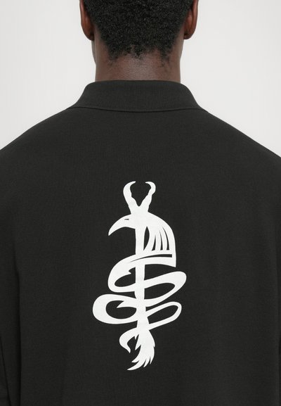 Schwarzes Poloshirt mit einem großen weißen Grafikdesign eines Vogels, der sich mit einer Schlange auf dem Rücken umschlingt. Glatte Textur und klassischer Kragen.