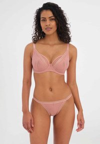 Soutien-gorge rembourré et string assorti en rose doux, avec un motif géométrique, des bretelles ajustables et un détail délicat à la taille.