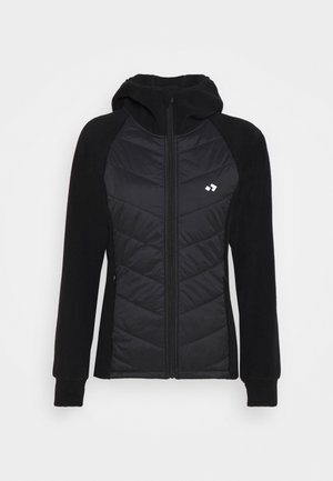 Veste noire à capuche avec panneau avant matelassé, fermeture éclair intégrale, manches longues et petit logo blanc sur la poitrine gauche.