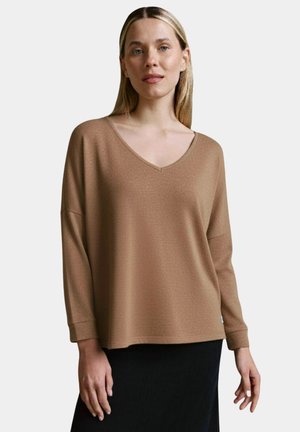 Braunes Langarm-V-Ausschnitt-Oberteil aus strukturiertem Stoff mit lockerer Passform, kombiniert mit einem schwarzen Rock. Die Ärmel reichen bis unter den Ellbogen.