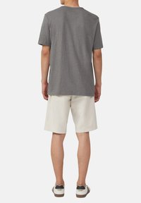 Grijze t-shirt met korte mouwen en een ronde hals, gecombineerd met lichte shorts en casual sneakers. Eenvoudig ontwerp; katoenmateriaal.