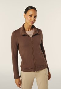 Giacca marrone con zip, dotata di colletto trapuntato, pannelli laterali testurizzati e corpo liscio. Maniche lunghe e due tasche frontali.