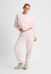 Hellrosa Sweatshirt mit rundem Ausschnitt und gerippten Bündchen, kombiniert mit passenden Jogginghosen mit elastischem Bund und Knöchel-Bündchen.
