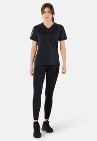 Zwarte sport T-shirt met een v-hals en korte mouwen, gecombineerd met zwarte leggings. De outfit heeft een strakke, aansluitende pasvorm voor optimale bewegingsvrijheid.