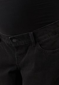 Black denim jeans with a fitted waist, featuring a button closure, front pockets, and a smooth texture. Visible stitching along the seams.