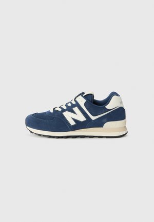 Blå og hvide New Balance-snøresko med ruskind og mesh overdel, snørelukning og polstret sål mod en ensfarvet hvid baggrund.