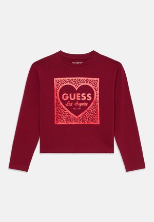 Bordo dugih rukava skraćeni majica od mekanog materijala, s dizajnom srca i natpisom "GUESS Los Angeles" u podebljanom fontu.